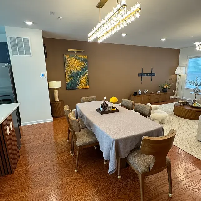 Dining and living area with soft furniture, warm-toned wood flooring, and coordinated interior woodwork design.